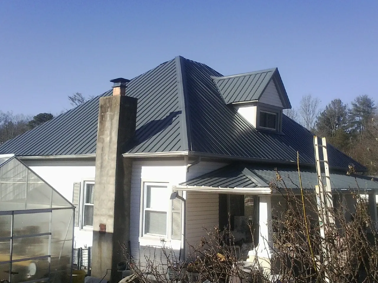 Dark blue standing seam metal roof on a white farmhouse with dormer — Slate & Tile Roof Repair by Roofing Brothers in Brewster