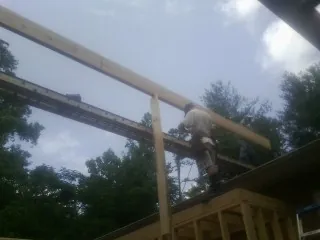Carpenter setting a ridge beam over a new addition frame — Ice Dam Removal by Roofing Brothers in Brewster