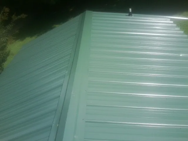 New green metal panels meeting at the ridge of a roof — Flat Roof Repair work by our crew in Brewster