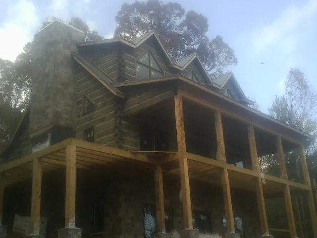 Stone chimney and dormers on a large log home with a timber porch in Brewster
